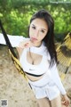 A woman in a white top and shorts sitting in a hammock.