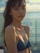 A woman in a blue bikini standing on a beach.