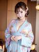 A woman in a blue kimono posing for a picture.