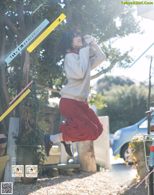 A woman jumping in the air in front of a bike.