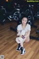 A woman sitting on the floor in a gym with boxing gloves.