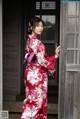 A woman in a red and white kimono standing in front of a door.