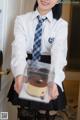 A woman in a school uniform holding a cake.