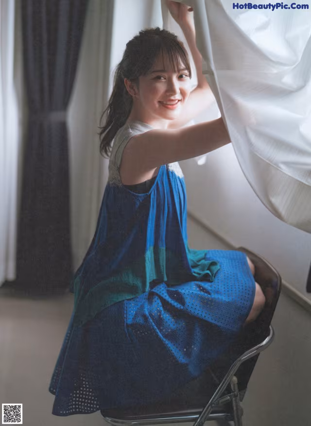 A woman sitting on a chair in front of a window.