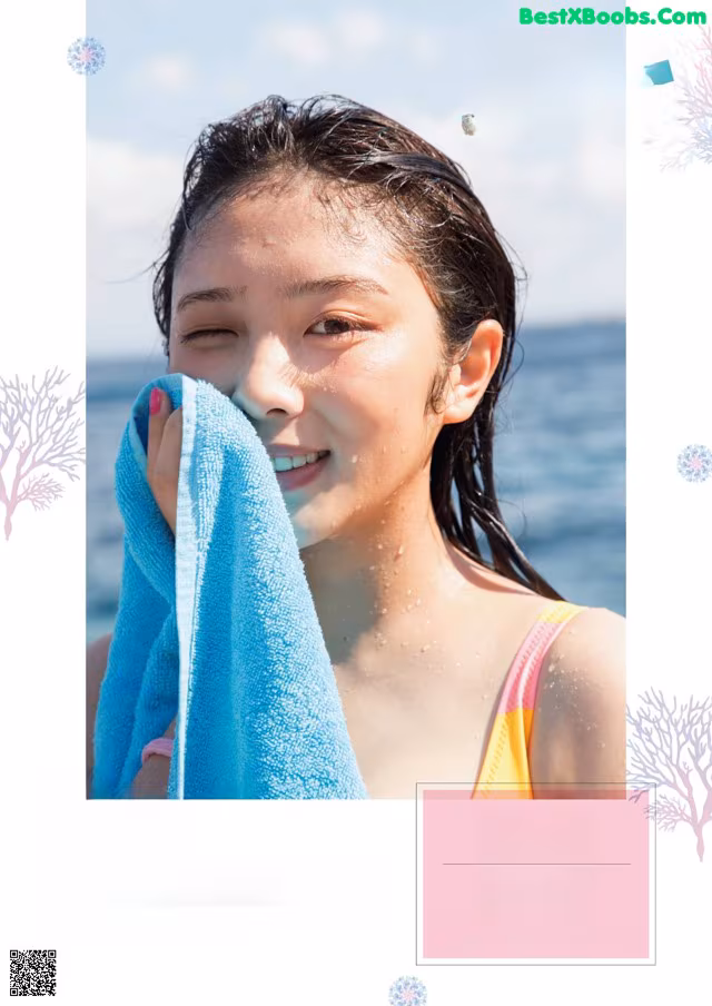 A young woman wiping her face with a towel.