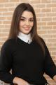 A woman in a black sweater and white shirt posing for a picture.