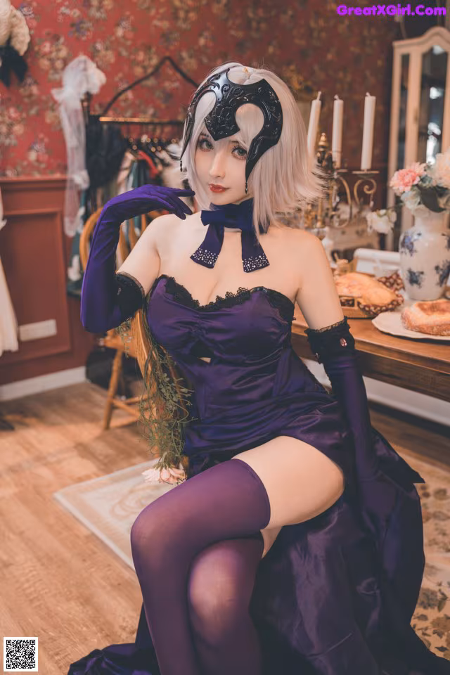 A woman in a purple dress sitting on a wooden floor.