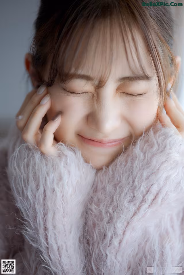A woman in a pink fur coat with her eyes closed.