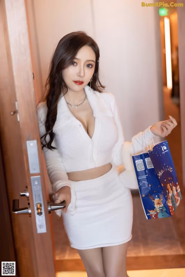 A woman in a white dress holding a shopping bag.