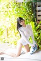 A woman sitting on top of a white couch next to plants.