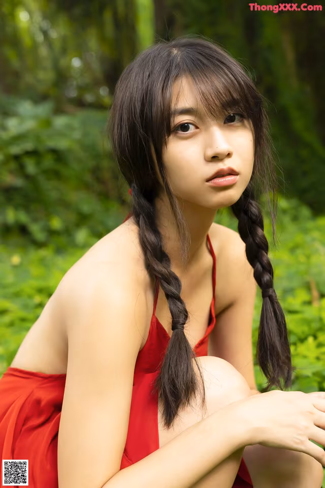 A woman in a red dress sitting on the ground.
