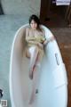 A woman sitting in a bathtub with her legs crossed.