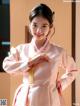 A woman in a pink hanbok is posing for a picture.