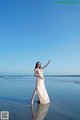 A woman in a long dress standing on the beach.