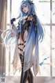 A woman with long blue hair standing in front of a window.