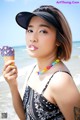 A woman holding an ice cream cone on the beach.