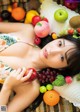 A woman laying on top of a bed covered in fruit.