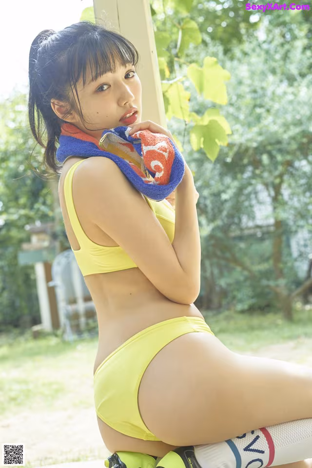 A woman in a yellow bikini sitting on a bench.
