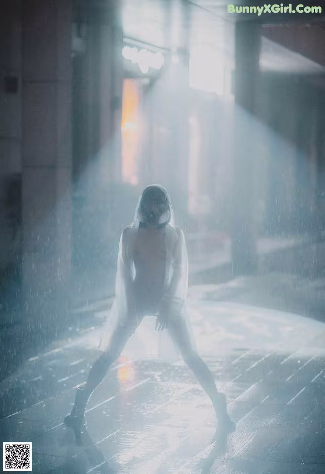 A woman in a white suit is standing in the rain.