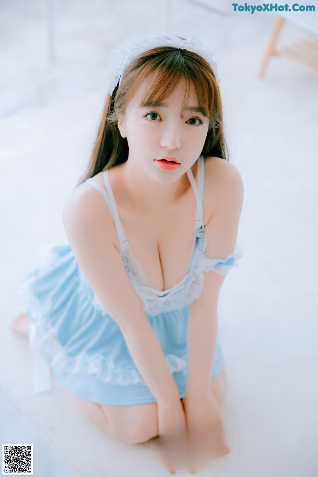 A woman in a blue dress sitting on the floor.