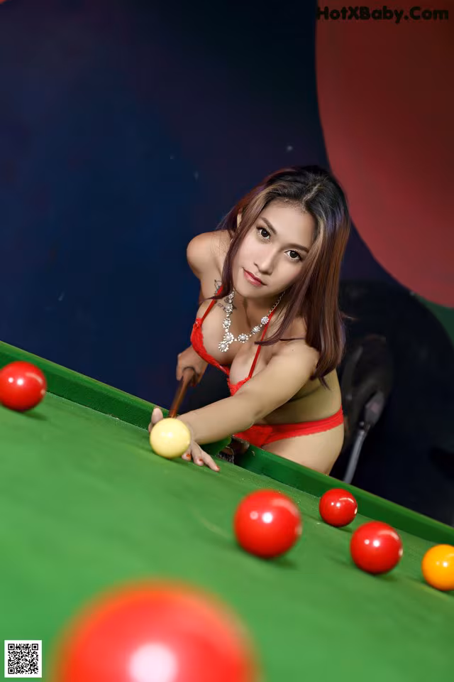 A woman in a red bikini playing pool.